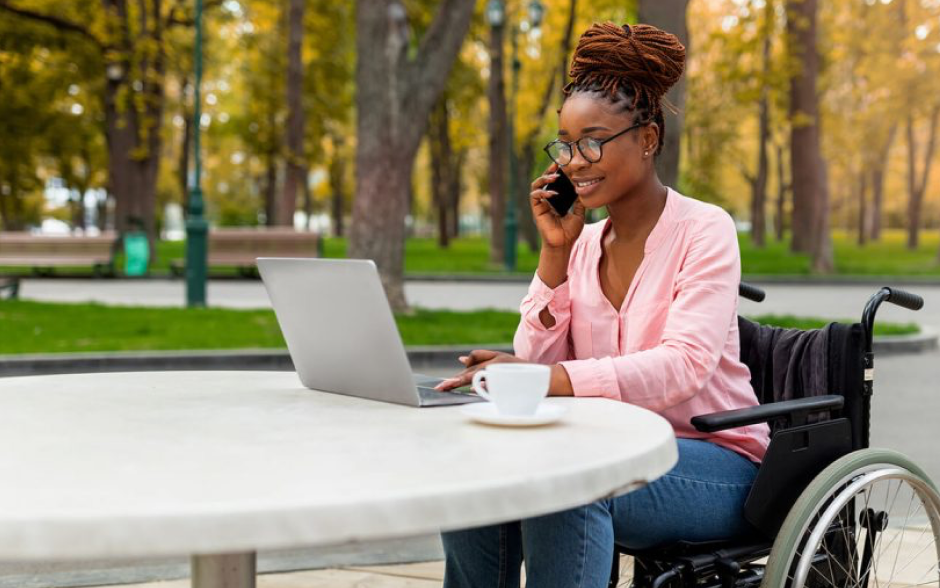 woman on the phone and her computer at a cafe in wheelchair 